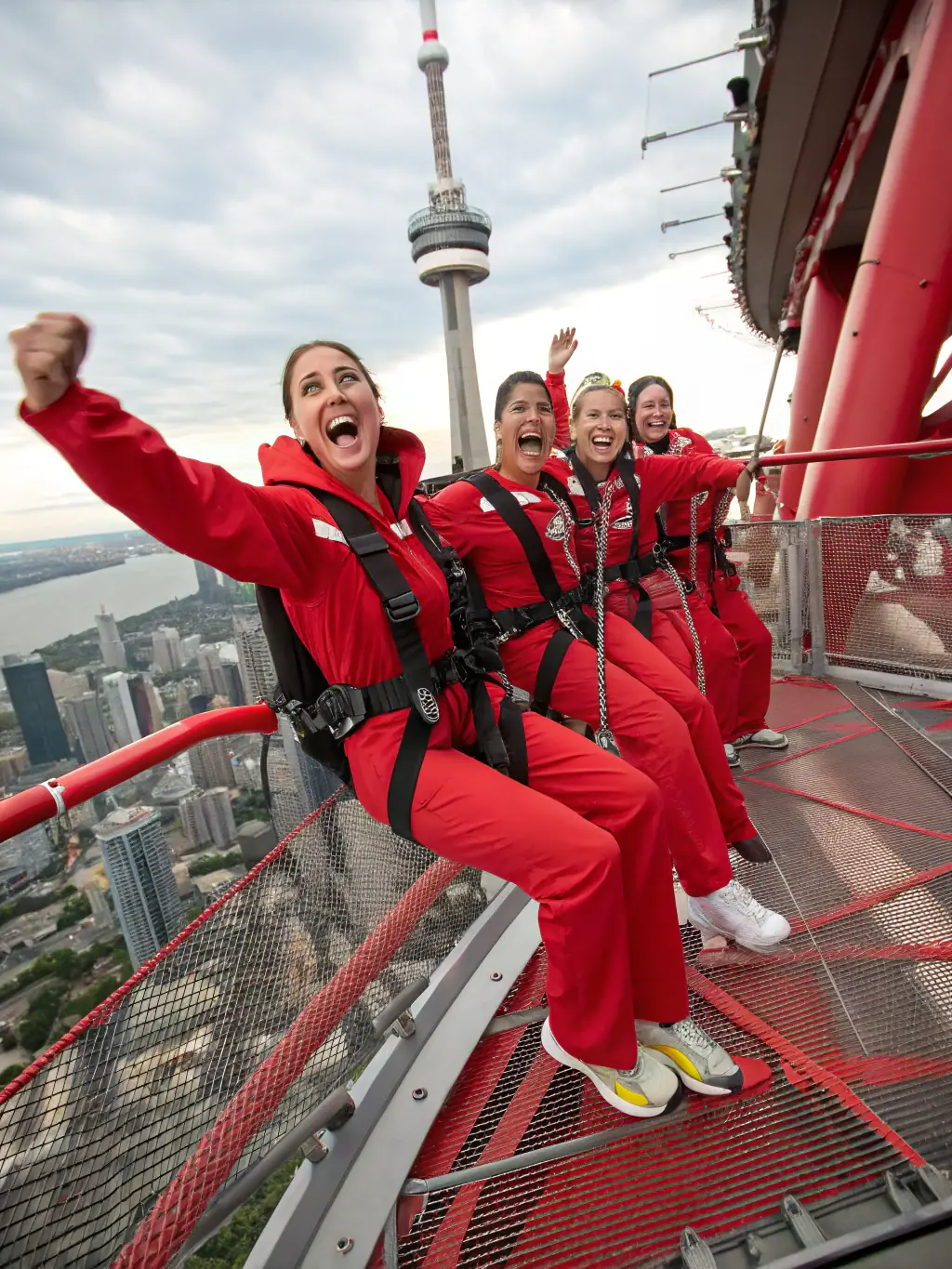 A thrilling, wide-angle shot of a group of people participating in the EdgeWalk, safely harnessed and smiling, with the city skyline as a backdrop.